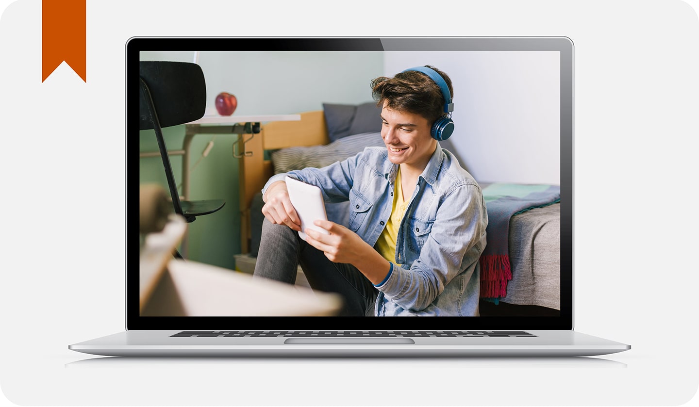 Chico sonriendo, mirando una tablet y escuchando música